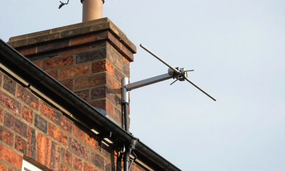 Outdoor TV aerial professionally mounted on house chimney with secure mast and coaxial cable, showing proper installation and weatherproof setup for long lifespan