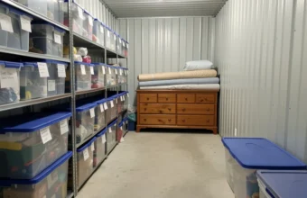 well organized self storage unit with clear plastic bins on metal shelves and a central walking path