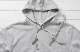 How to style hoodie strings with barrel knot, fishtail braid, and bead embellishments on a grey hoodie flat lay