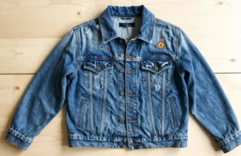 Flat lay of denim jacket with assorted embroidered and woven apparel patches for DIY customization
