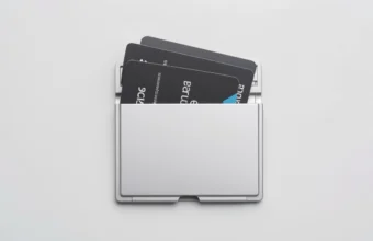 Silver aluminum cardholder wallet with pop-up mechanism displaying credit cards, ID, and folded cash on marble surface