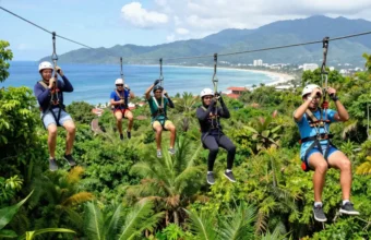 A diverse team of young professionals enjoying outdoor team building in Puerto Vallarta as they zip-line through the lush jungle canopy with Banderas Bay in the background.