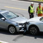 Photorealistic image of a car accident with two damaged vehicles, emergency responders assisting at the scene, and a bystander taking photos on a smartphone, illustrating post-accident safety and documentation.